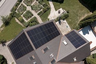 Draufsicht aus der Vogelperspektive auf ein Haus mit Garten und montierter PV-Anlage.