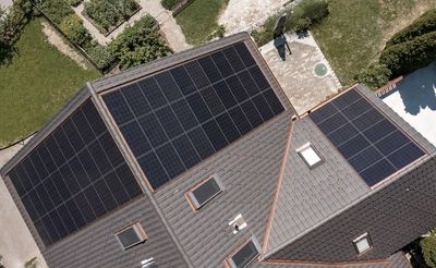 Draufsicht aus der Vogelperspektive auf ein Haus mit Garten und montierter PV-Anlage.