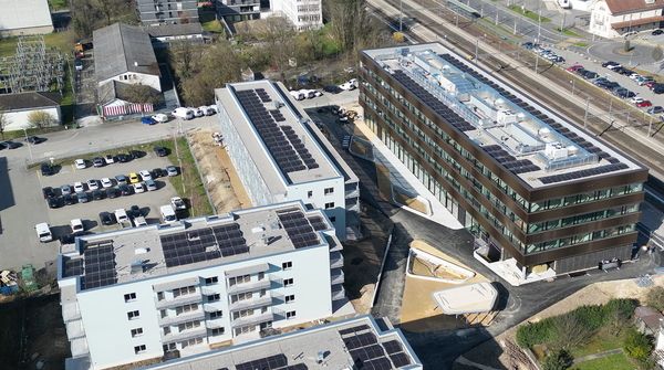 Luftaufnahme eines modernen Neubaus der Bricks AG mit einer grossen Solaranlage auf dem Dach. 