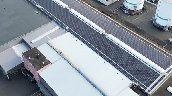 Luftaufnahme der grossen Industriehalle der Moser Maschinen AG mit einer grossen Solaranlage auf dem Dach. 